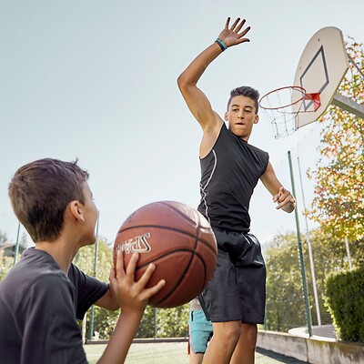 Children playing basketball in the outdoor adventure area