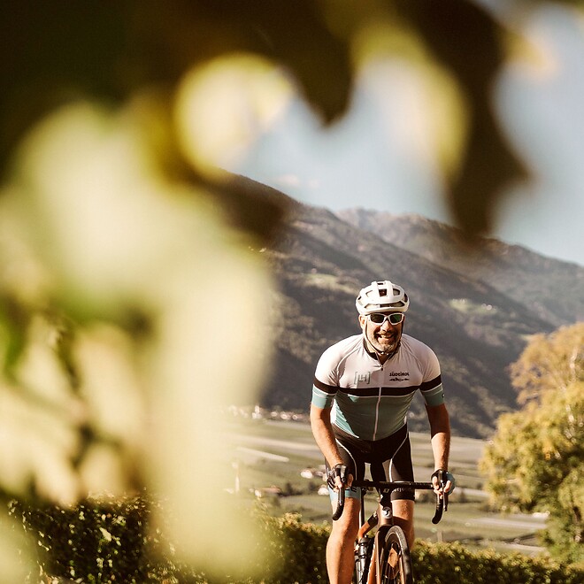 Rennradfahrer fährt durch Obstplantagen in Südtirol