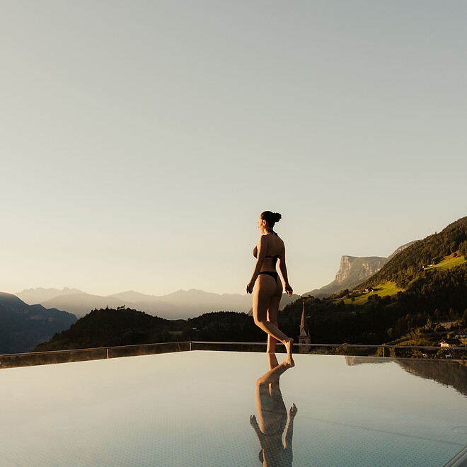 Frau spaziert am Infinity Sky Pool bei Sonnenaufgang