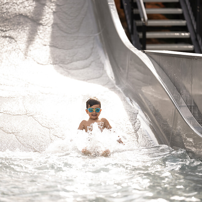Junge rutscht auf der Wellenrutsche im Hotelgarten