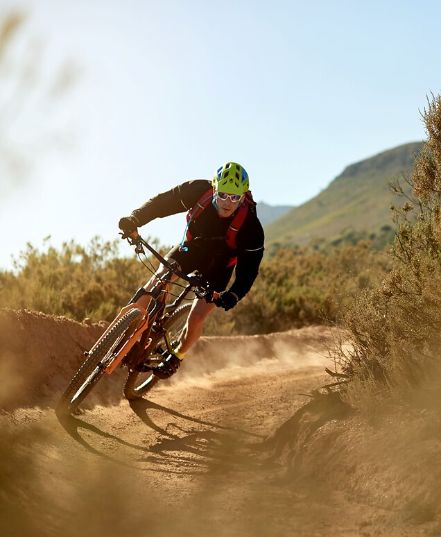 Mann fährt mit dem Mountainbike über erdigem Trail im Berg