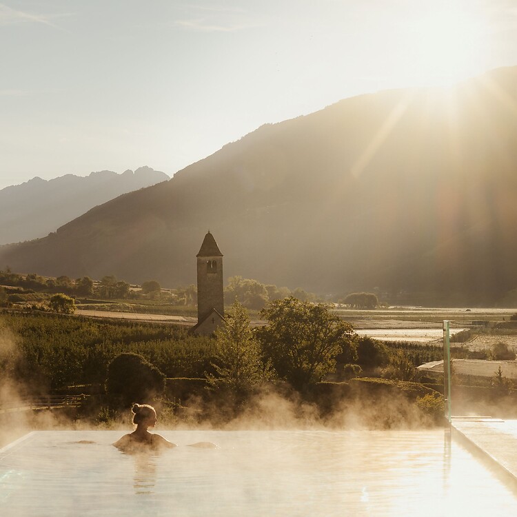 Frau genießt im Infinity Skypool die traumhafte Aussicht bei Sonnenaufgang