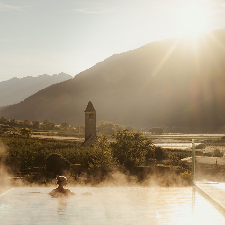 Frau genießt im Infinity Skypool die traumhafte Aussicht bei Sonnenaufgang