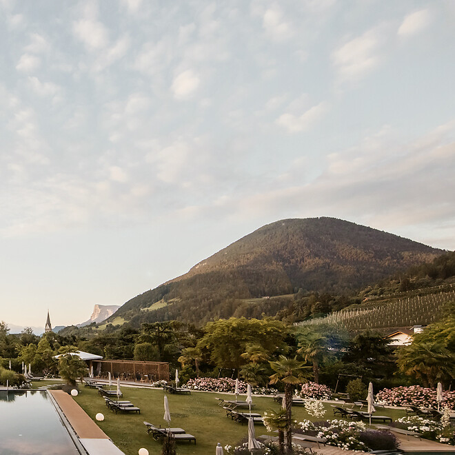 Infinity Outdoorpool und mediterraner Hotelgarten umgeben von Bergen