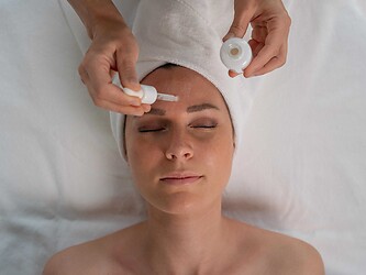 Donna sdraiata su un lettino che riceve un trattamento viso rilassante e di alta qualità