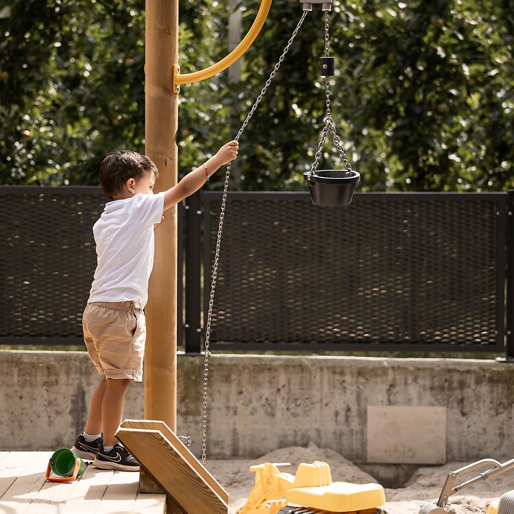 Junge spielt im hoteleigenen Outdoor-Spielplatz im Sandkasten