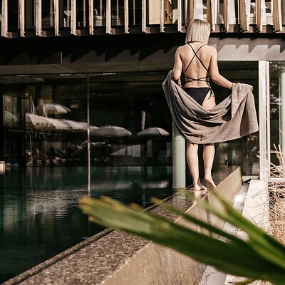 Frau spaziert entlang des Outdoor-Sportpools vor dem Wellnesstower