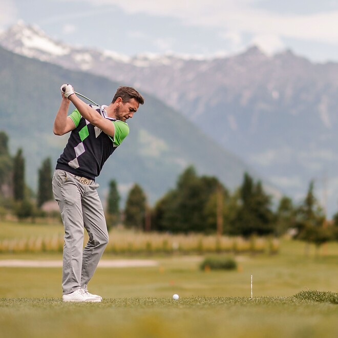 Mann beim Golfen mit Bergpanormablick