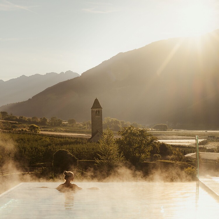 Frau genießt im Infinity Skypool die traumhafte Aussicht bei Sonnenaufgang