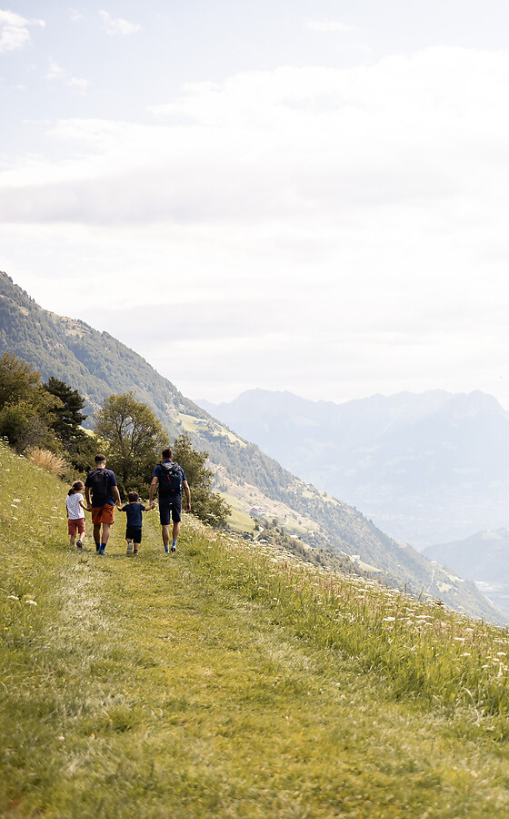Familie beim Wandern hoch oben in den Bergen mit Aussicht auf Tal