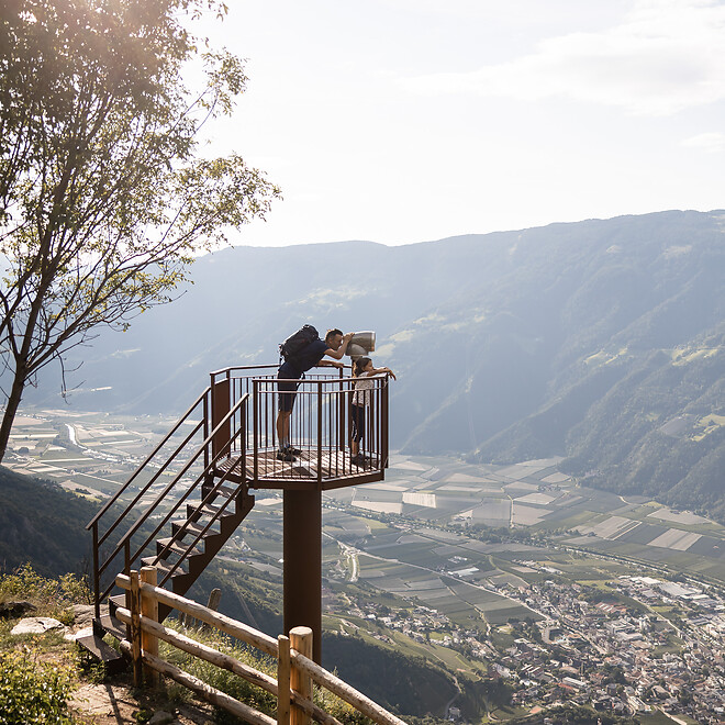 Father and daughter looking through a telescope over the entire valley and mountains
