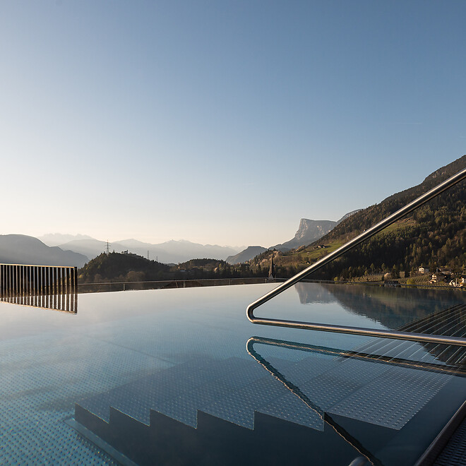 Infinity Pool nello Sky Spa con vista sulle Dolomiti e sole basso all’orizzonte