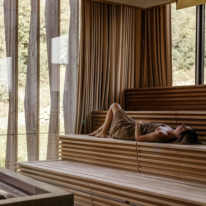 Donna sdraiata nella sauna con vista sul giardino termale
