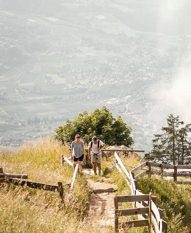 Uomo e donna che camminano in montagna con ampia vista sulla valle